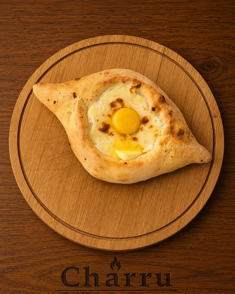 An Adjarian khachapuri with a raw egg yolk and a pat of butter on melted cheese, on a round wooden board
