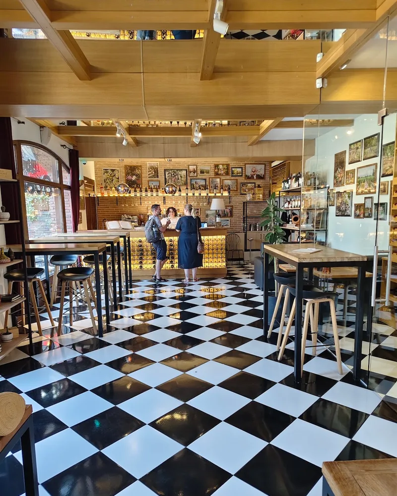 Wine bar with a checkerboard floor and high tables at Château Mukhrani Wine Bar