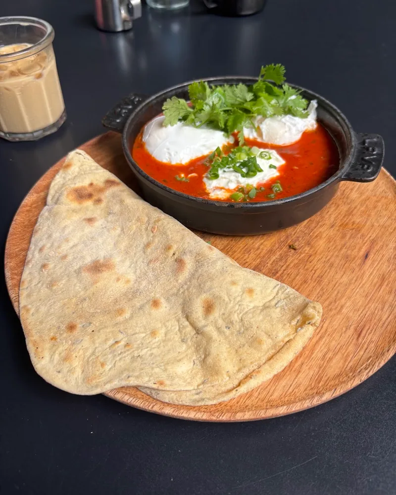 Shakshuka with poached eggs, herbs and flatbread on a wooden board at Coffee Lab (Chavchavadze Ave)
