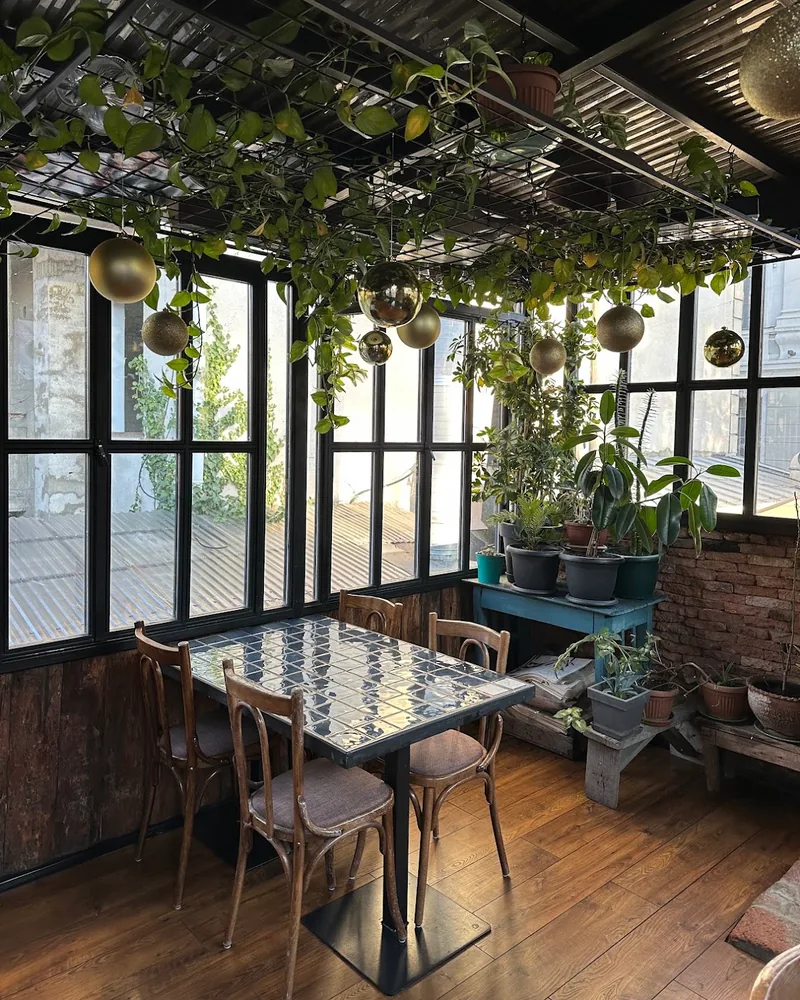 Enclosed veranda with tiled table and hanging plants at Chveni