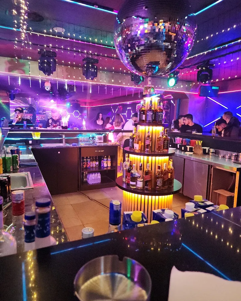 Nightclub bar counter with tiered bottle display and disco ball at Club Arena