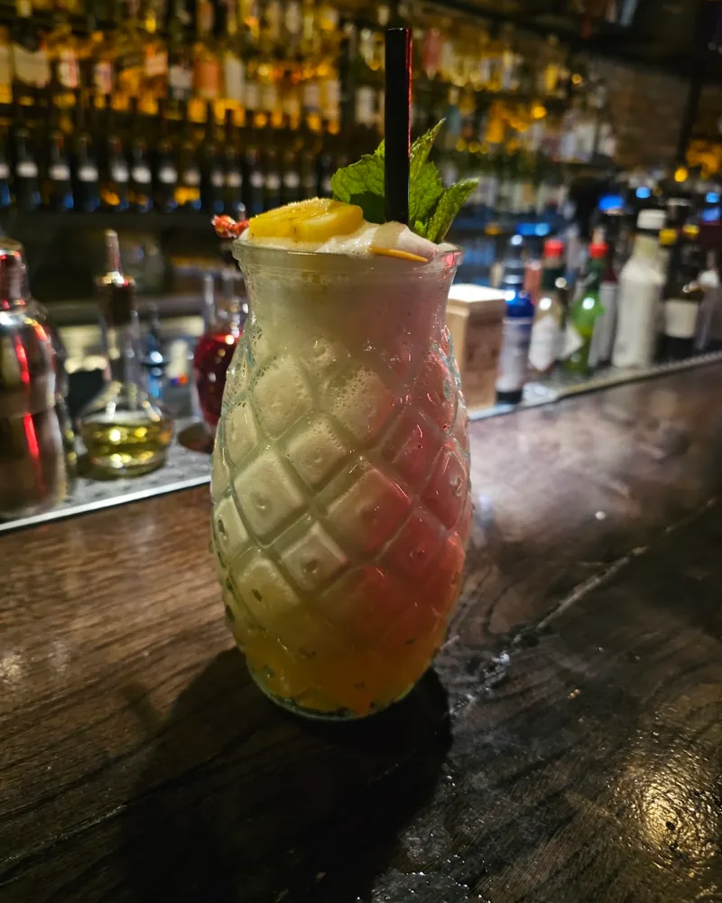 Cocktail in a pineapple-shaped glass with mint and citrus at Cocktail Factory