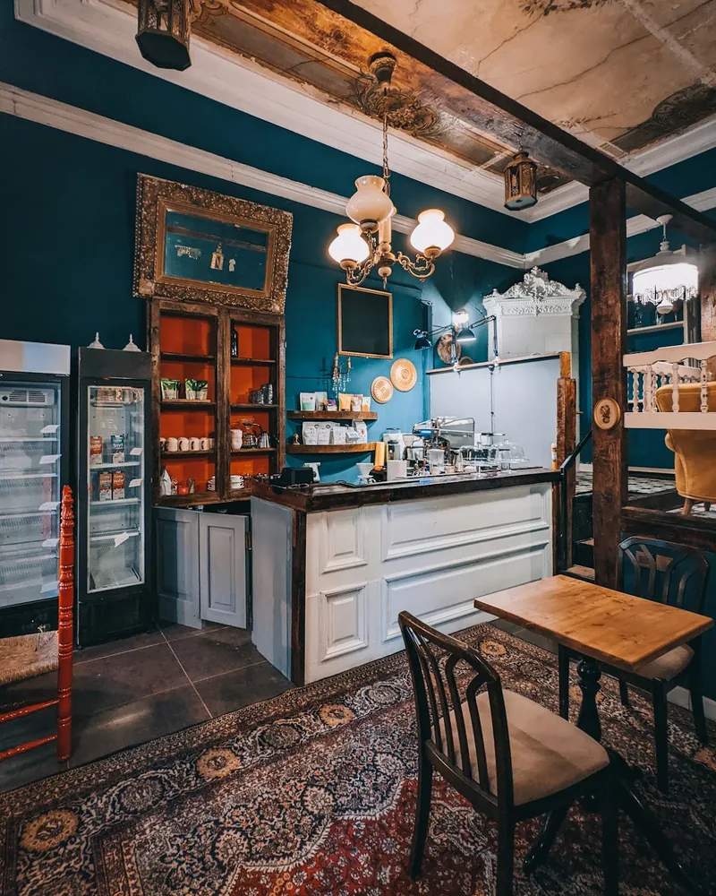 Teal cafe room with a panelled counter and a brass chandelier at Coffee Place
