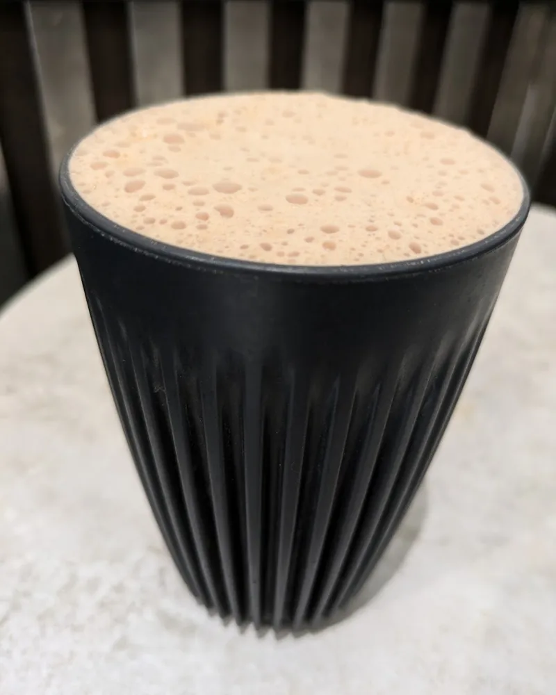 Foamy beverage in a reusable ribbed black cup at Coffee Space