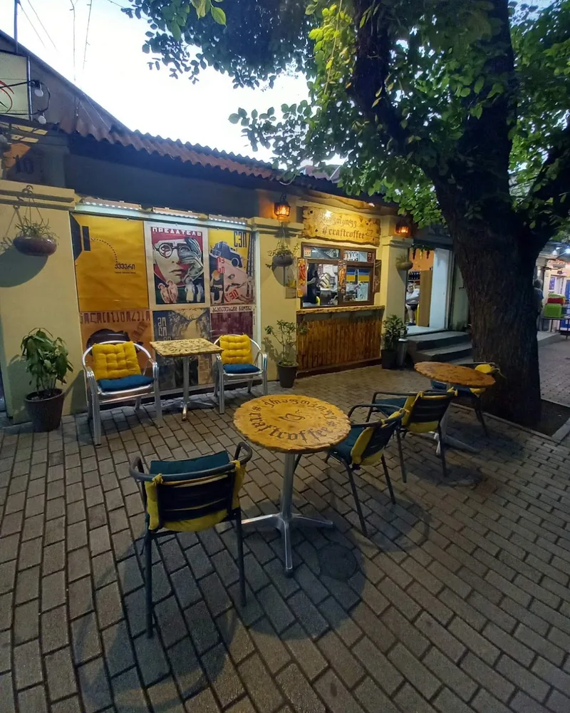 Outdoor patio seating with wooden tables and tree at Craft Coffee