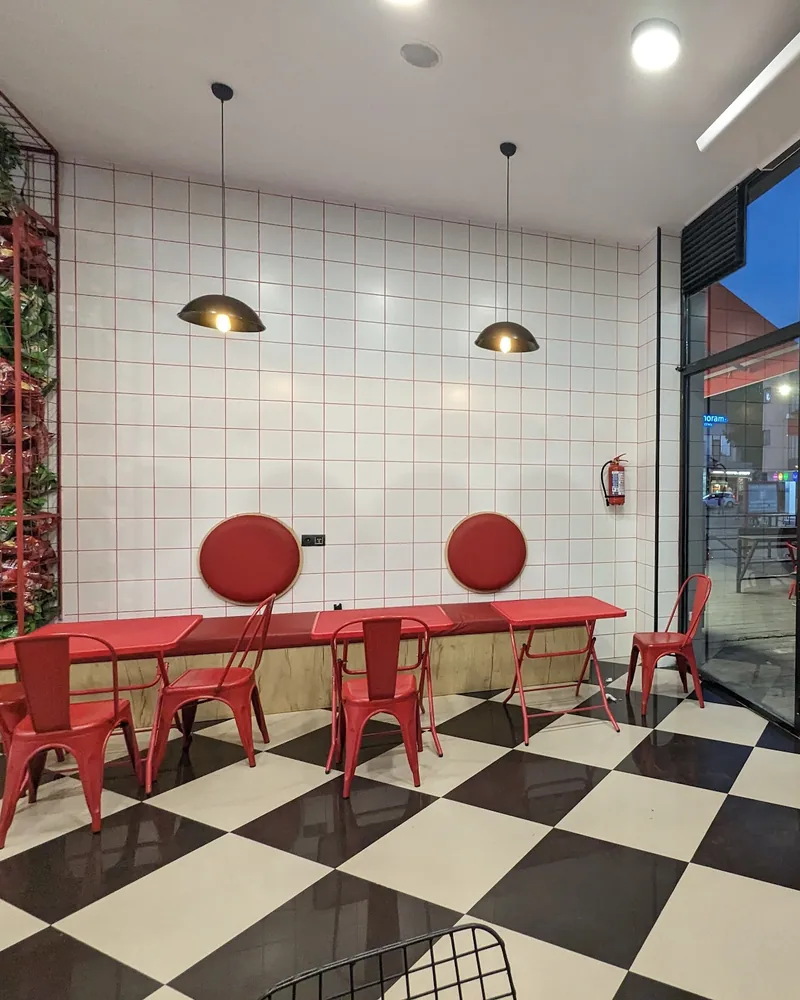 Checkered floor dining area with red chairs and tiled wall at Craft Food