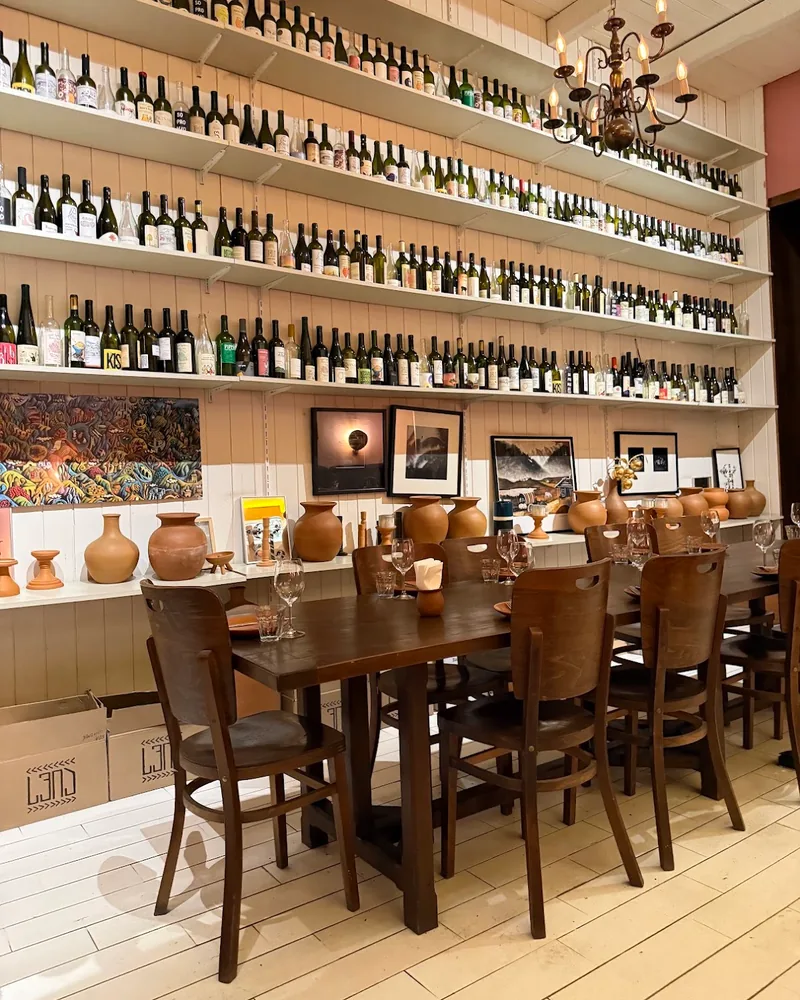 Wooden dining table and wall lined with wine bottles at Craft Wine