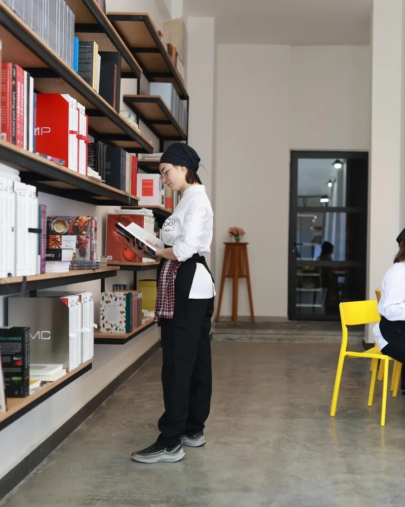 Library and study hallway with bookshelves and yellow chairs at Culinary Academy of Georgia