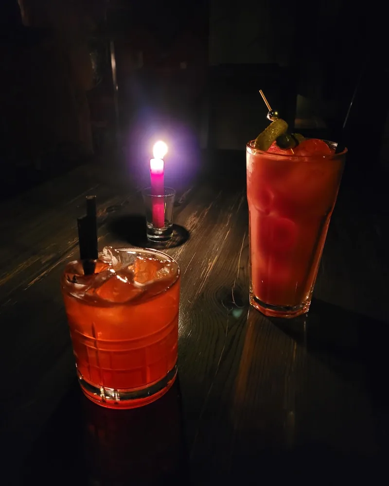 Two red cocktails on a dark candlelit table at D22 Bar