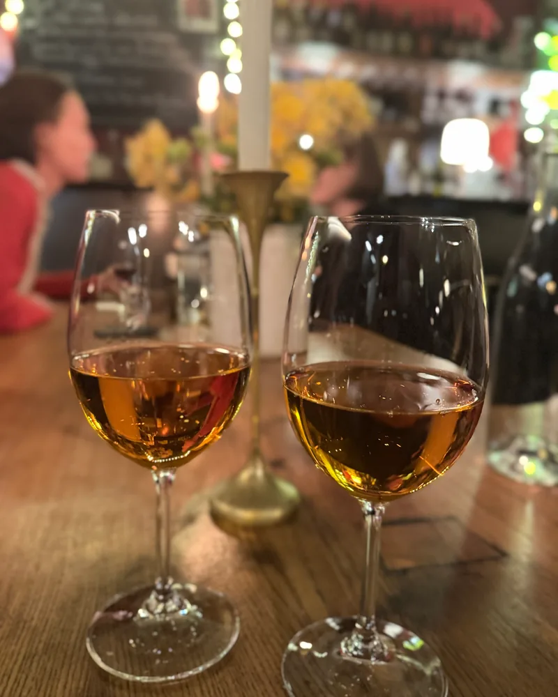 2 glasses of amber wine on a wooden bar table by candlelight at Dadi Wine Bar