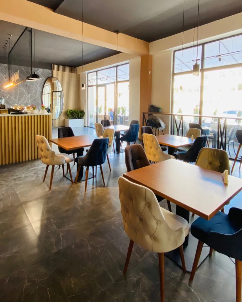 Cafe dining area with wooden tables and upholstered chairs at Daily Dose