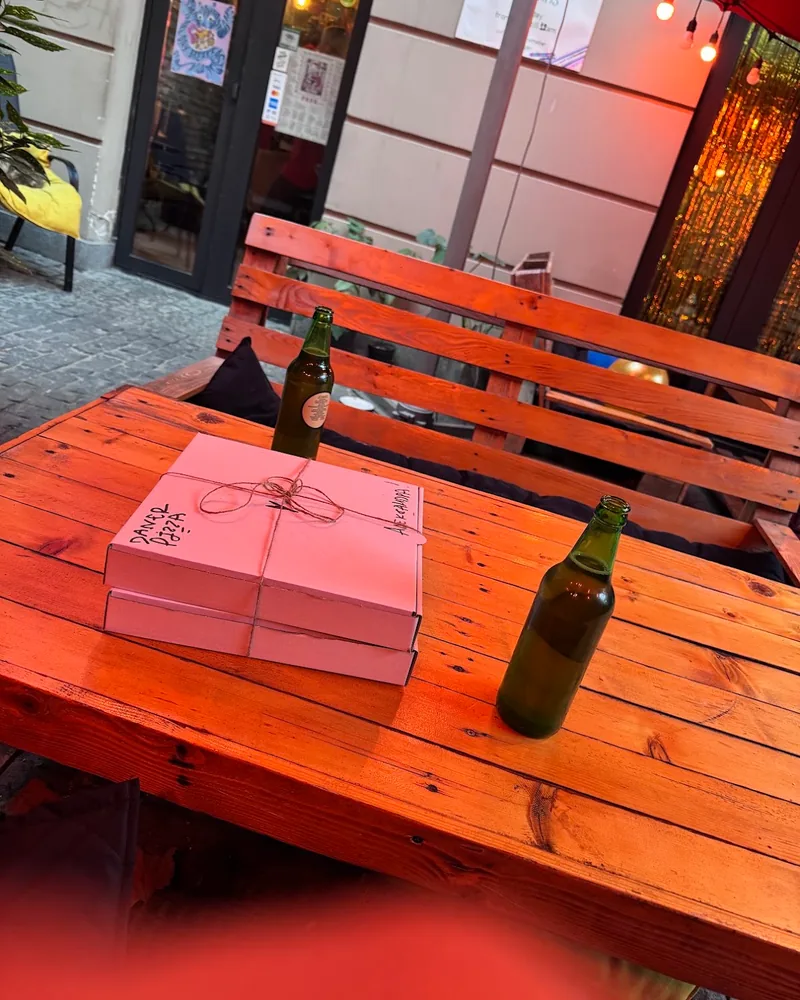 Outdoor wooden bench and table with pizza boxes at Daner Pizza