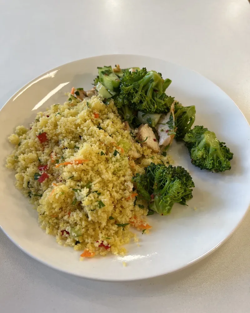 Couscous with broccoli and chicken on a white plate at DeGusti