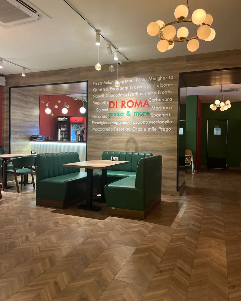 Dining area with green leather booth and branded wood wall at Di Roma