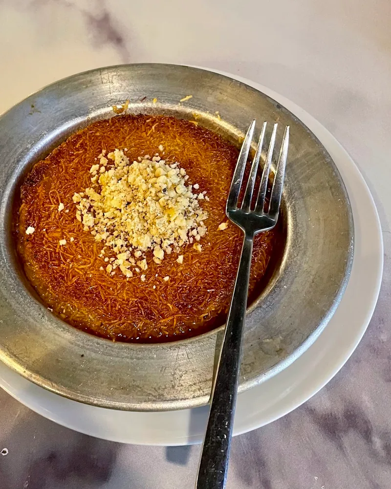 Kunefe topped with crushed nuts in a metal pan at Elit Restaurant
