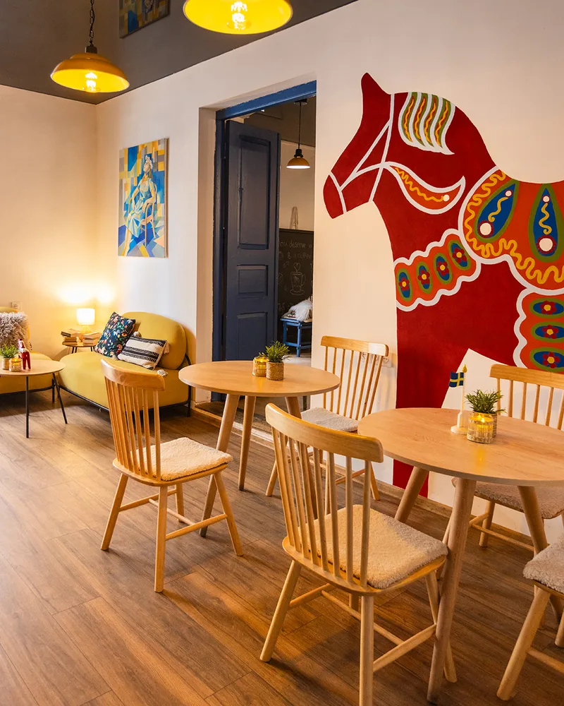 Cafe seating with wooden chairs and dalahäst wall mural at Fika Swedish Cafe