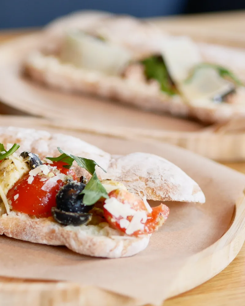Open-faced sandwich with tomatoes, cheese, and olives on flatbread at Fiorino