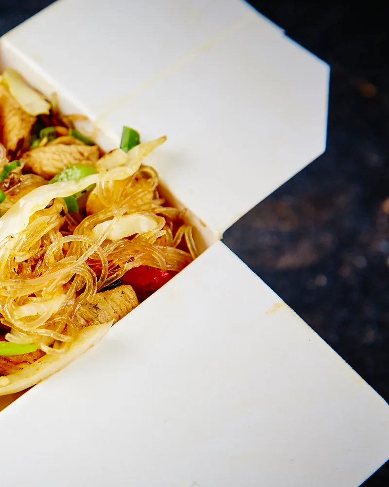 Glass noodles with chicken and vegetables in an open takeout box at Fire Wok (Saburtalo)