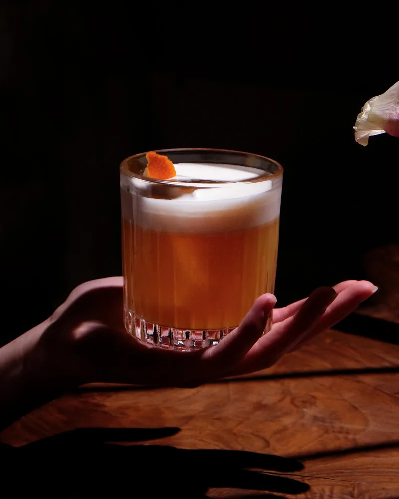 Sour cocktail with citrus foam and orange peel garnish at Flying Cafe
