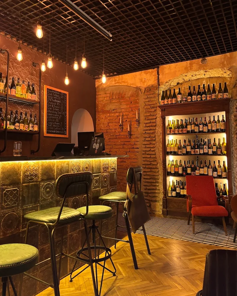 Tiled bar counter with green barstools and wine cabinet at Flying Cafe