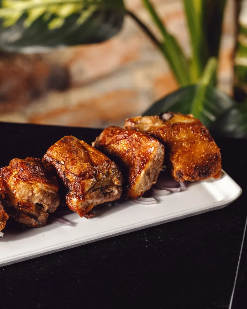 Crispy roasted pork ribs on a rectangular white plate at Fragment