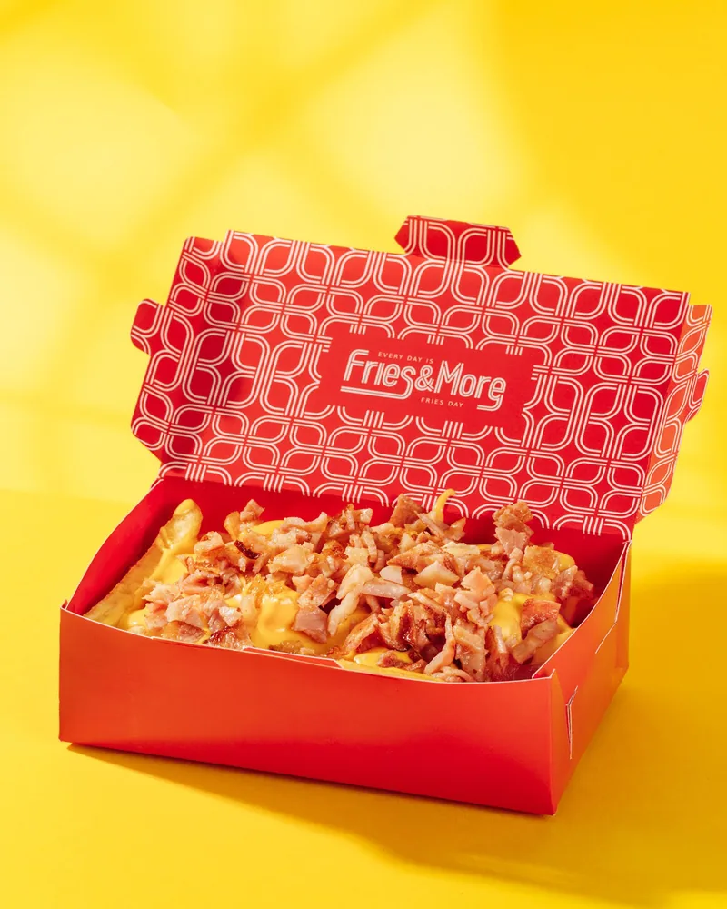 Loaded fries with cheese and bacon bits in a takeout box at Fries & More