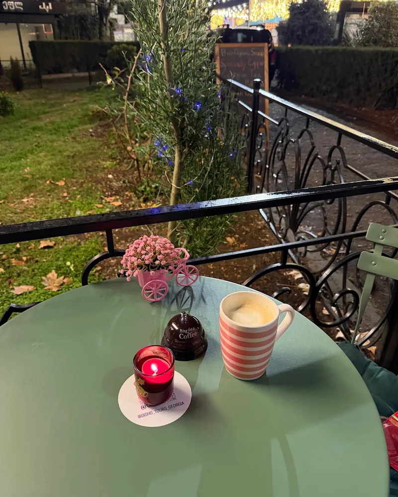 Latte in a striped mug on an outdoor table at Gisho Specialty Coffee