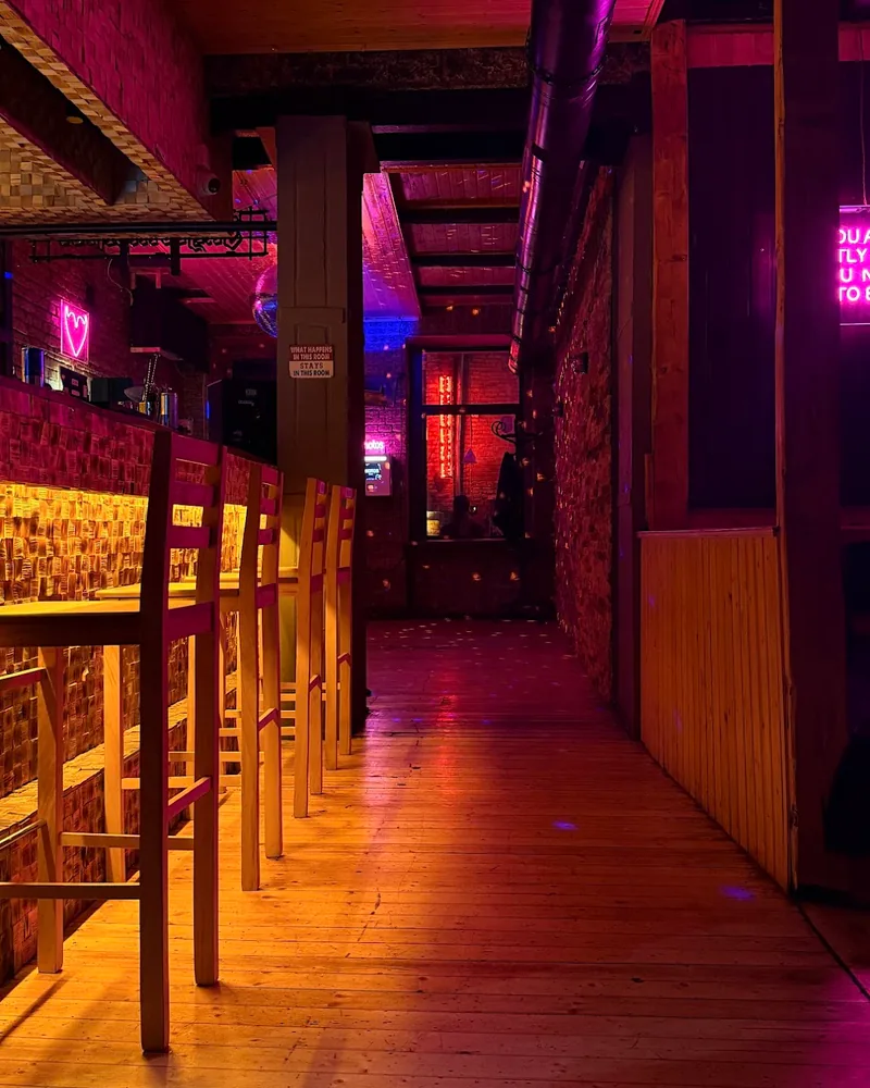 Dimly lit hallway and bar area with neon pink lighting at Glitch Bar