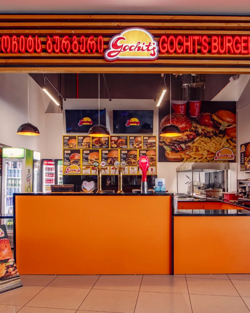 Bright orange service counter and illuminated brand signage at Gochits Burger