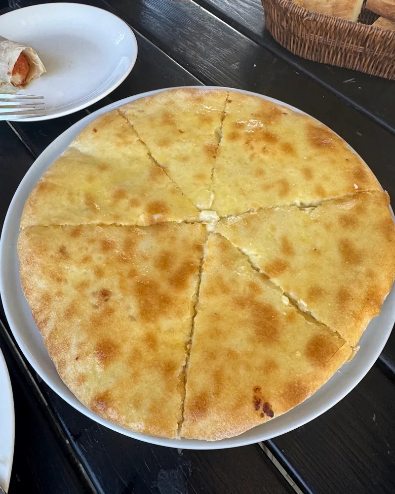 Imeruli khachapuri sliced into segments on a white plate at Golden Moon