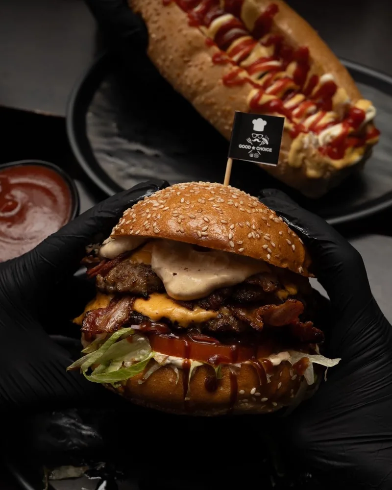 Bacon cheeseburger held in gloved hands at Good Choice