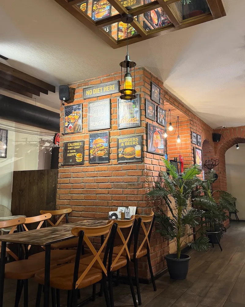 Exposed brick dining area with posters and wooden chairs at Good Choice