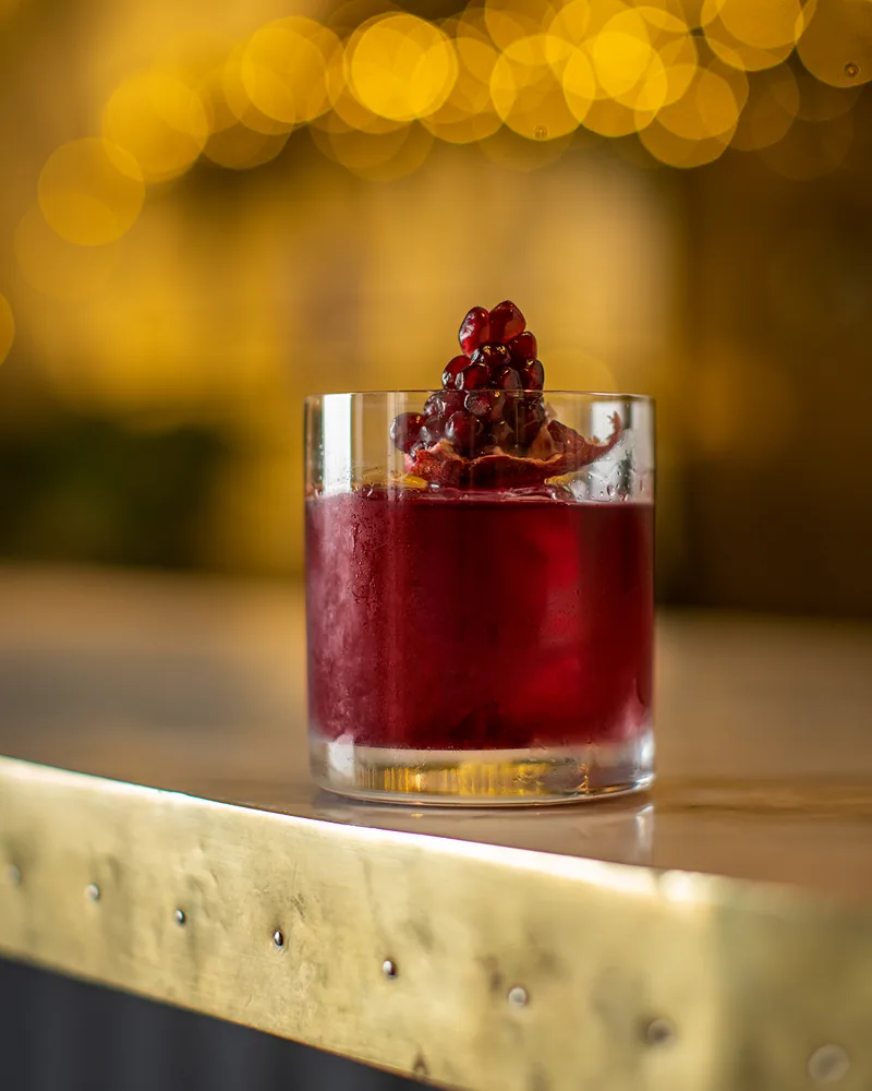 Dark red cocktail in a rocks glass with pomegranate garnish at Graali Bar