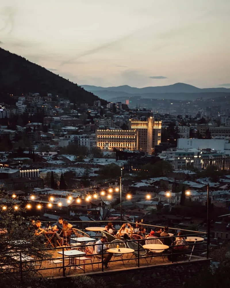 Terrace seating overlooking the city at dusk at Grilisi City View Bar
