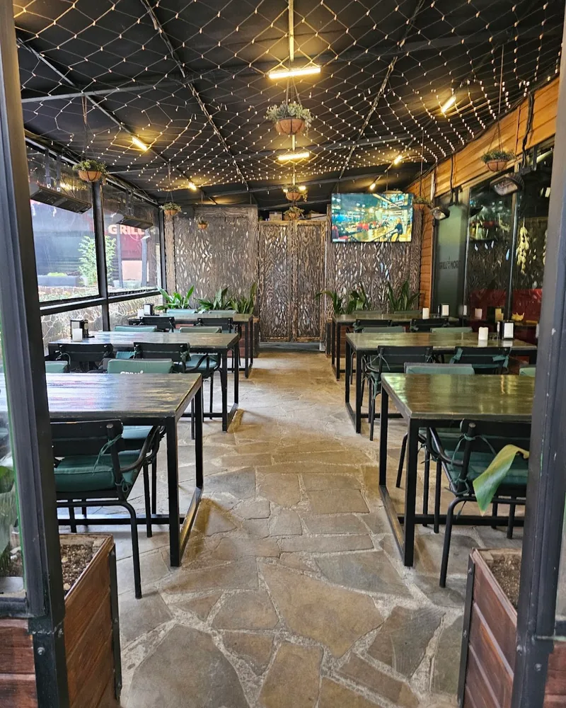 Covered terrace seating area with stone flooring at Grill More