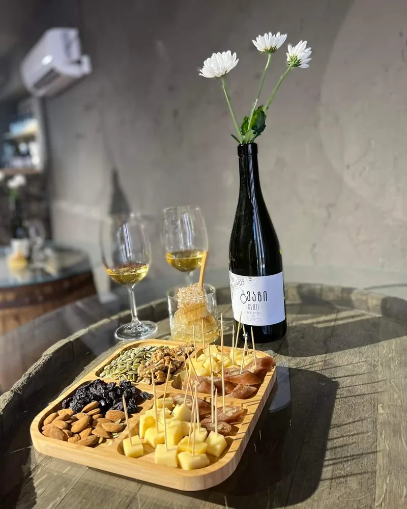 Wine bottle with flowers and tasting glasses with snack platter at Gvazi Winery