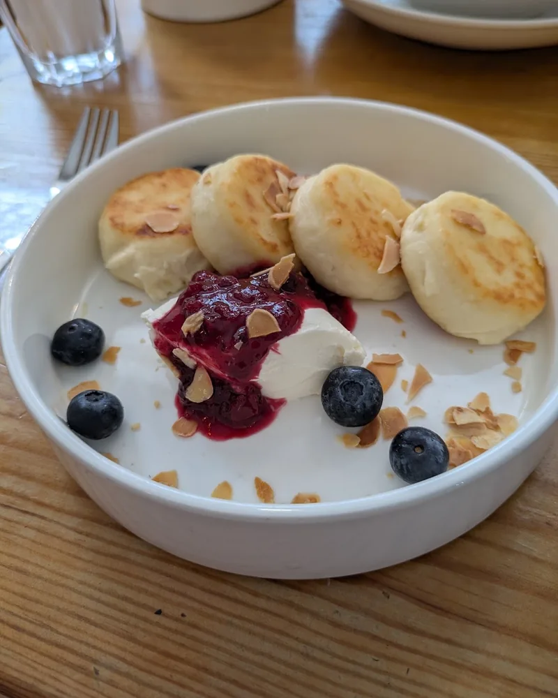 Syrniki with berry sauce, sour cream and blueberries at HURMA