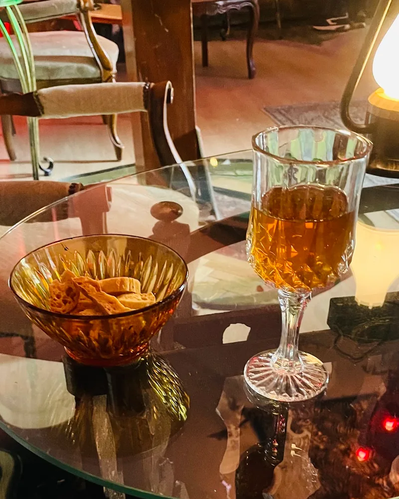 Amber drink in a crystal goblet with bowl of snacks at Impulse