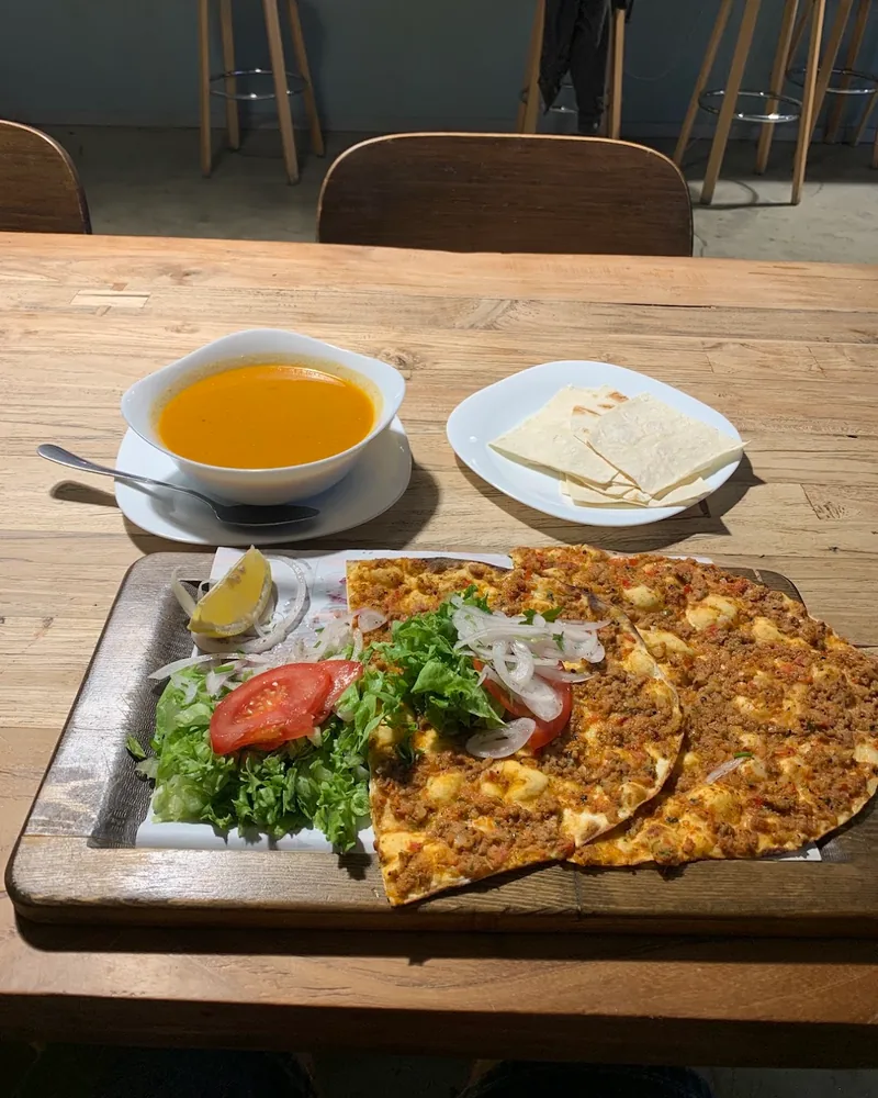 Lahmacun on a wooden board with lentil soup and flatbread at Istanbul Kebab’s