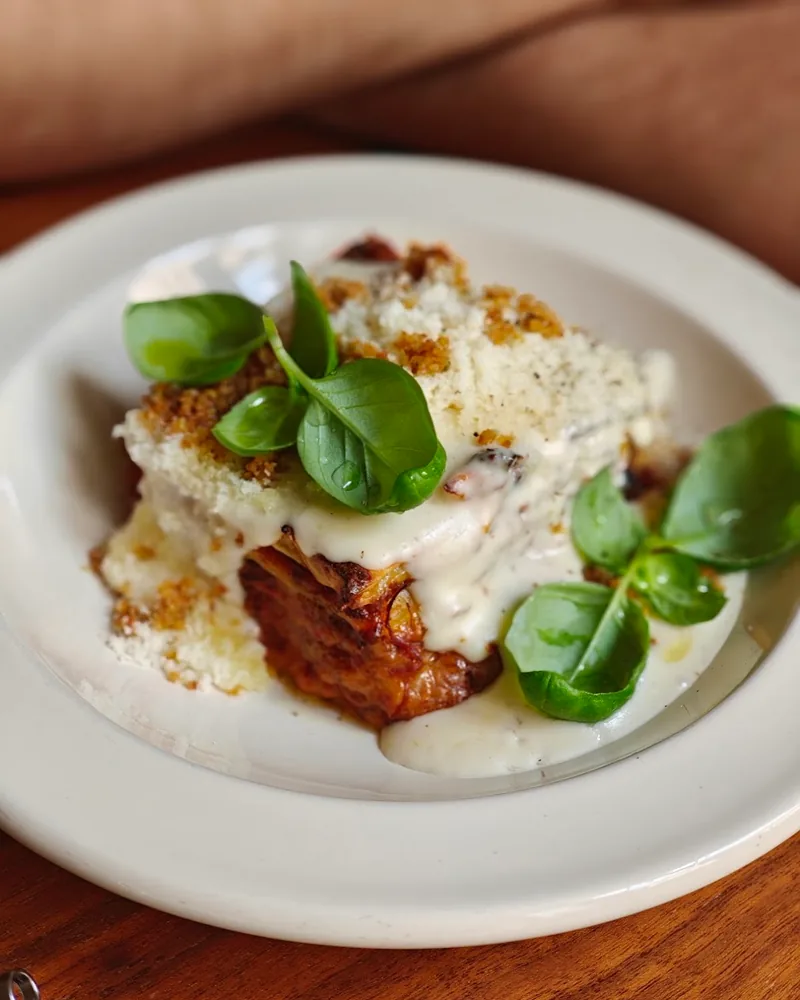 Lasagna with white sauce and basil on a white plate at Italian Pasta