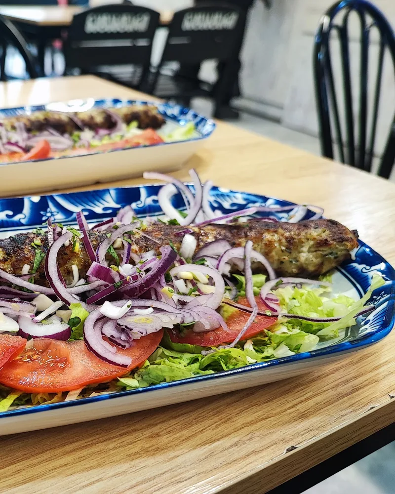 Lula kebab with onions and tomatoes on a patterned platter at Joker Shaurma