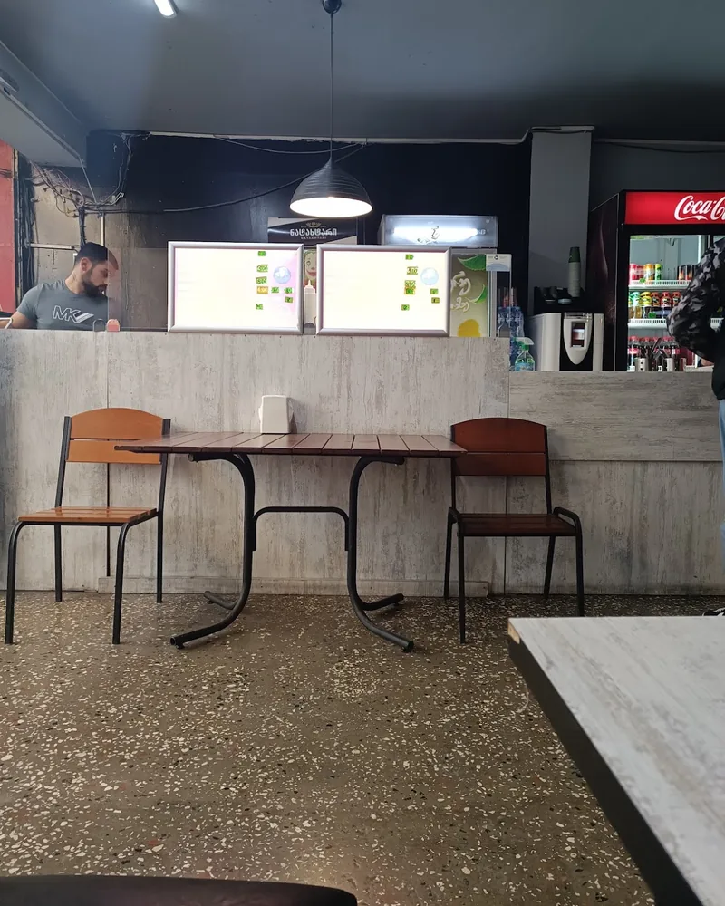 Dining area with simple table and chairs in front of order counter at Joker Shaurma