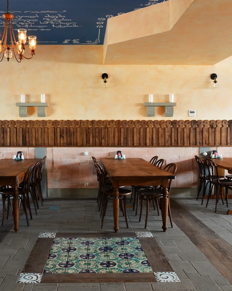 Dining room with wooden tables and ornate ceiling at Kakhelebi