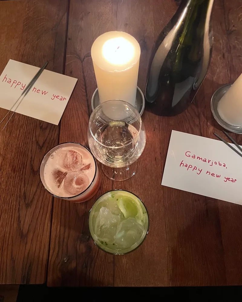 Cocktails and wine on a wooden table with candles at Kancellaria Natural Wine Bar