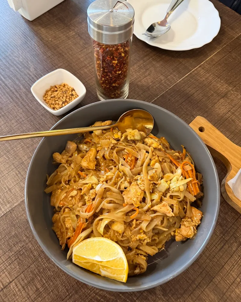 Pad thai with lemon wedge and spoon in a grey bowl at KaPaoBox