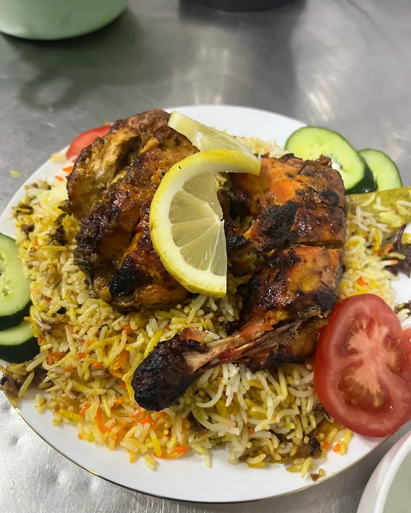 Chicken biryani garnished with lemon and cucumber slices at Karak House