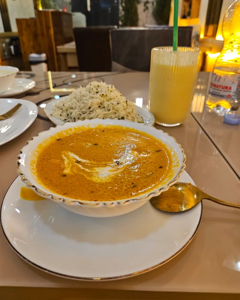 Bowl of curry served with rice and mango lassi at Karak House