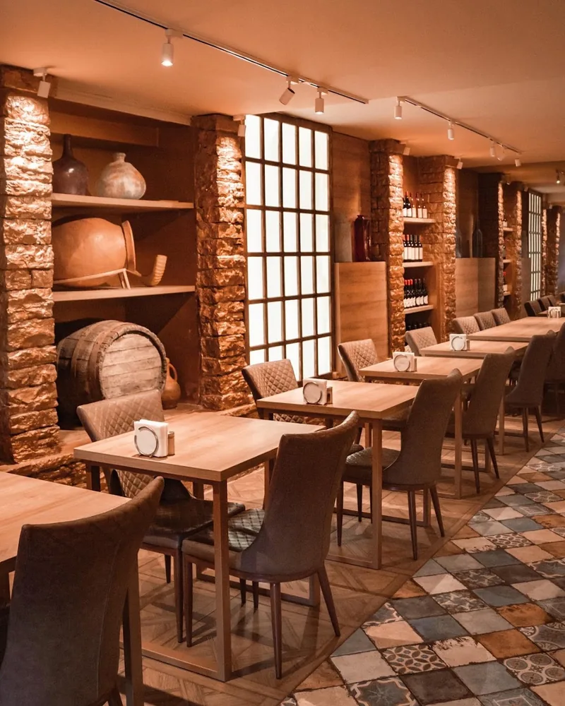 Dining room with brick columns, rustic wine barrel and wooden tables at Khinkali Bar N1