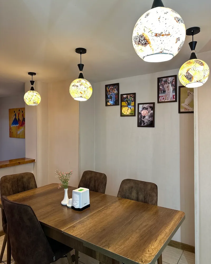 Dining table and chairs under pendant lamps at Khushi Indian Restaurant