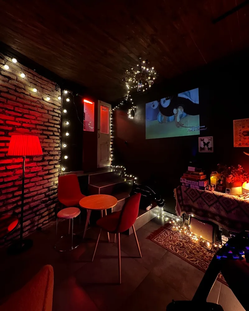 Dimly lit bar seating area with projector screen at Kiki Bar